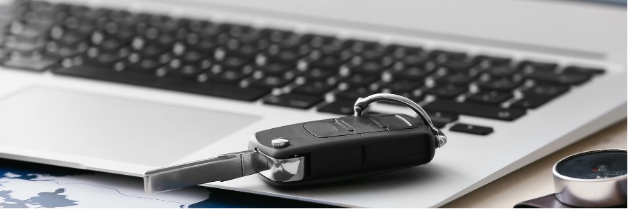 Black car key fob beside electronic handbrake.