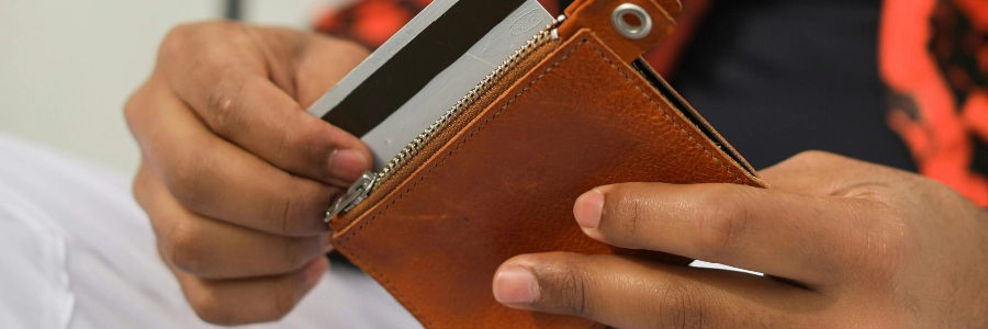 Man pulling a credit card out of his brown wallet