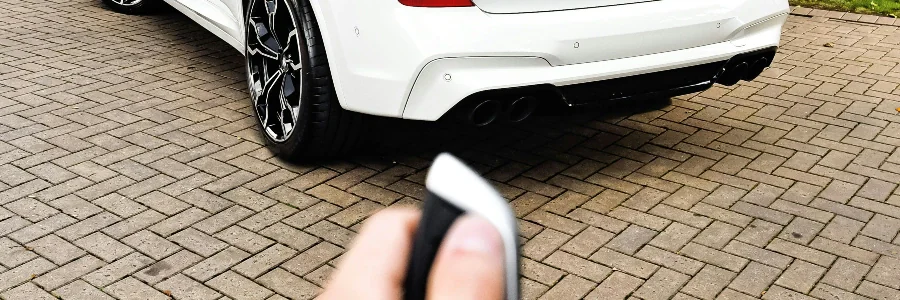 person holding a key fob pointed at a car
