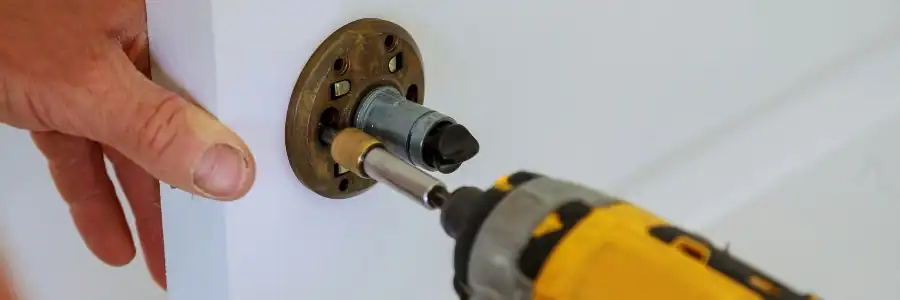 screwing a new lock onto a door