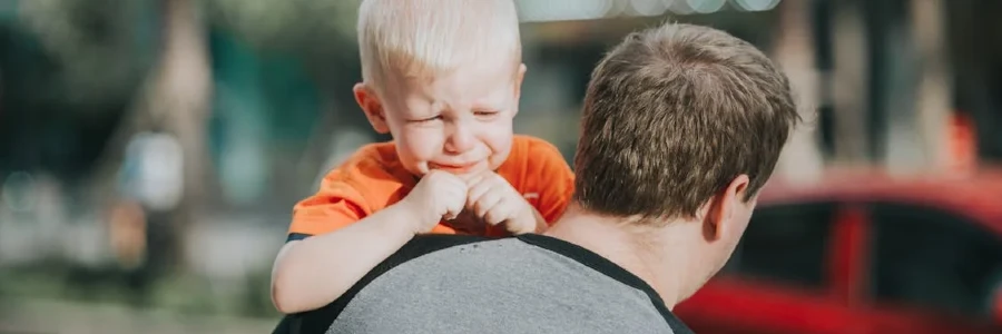 A father carries his crying son outdoors