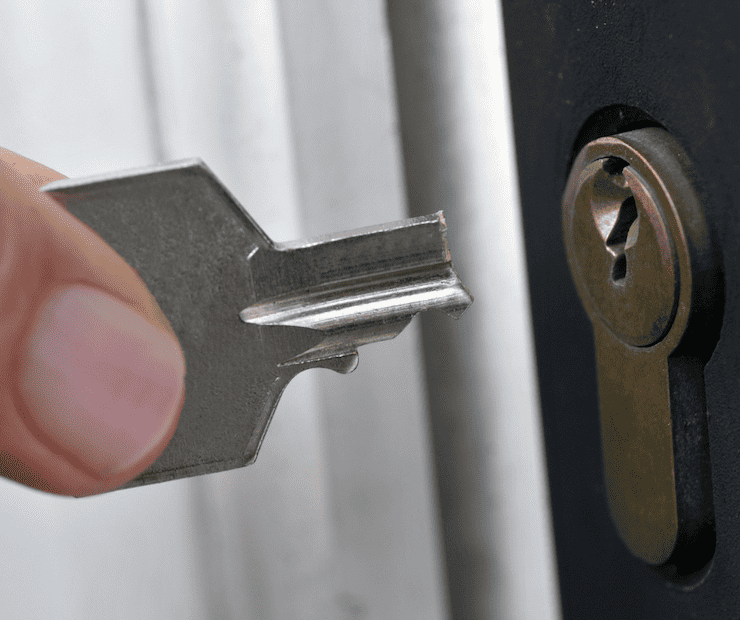 Half of a broken key being held by a hand The other half is in the keyhole